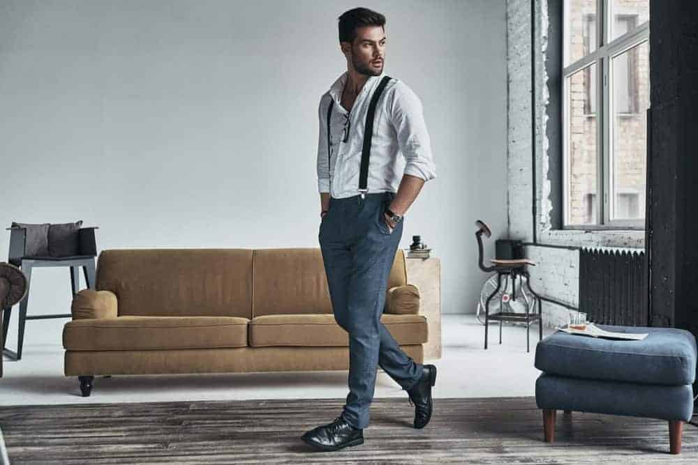 Male model in stylish clothing striking a pose in a chic living room.