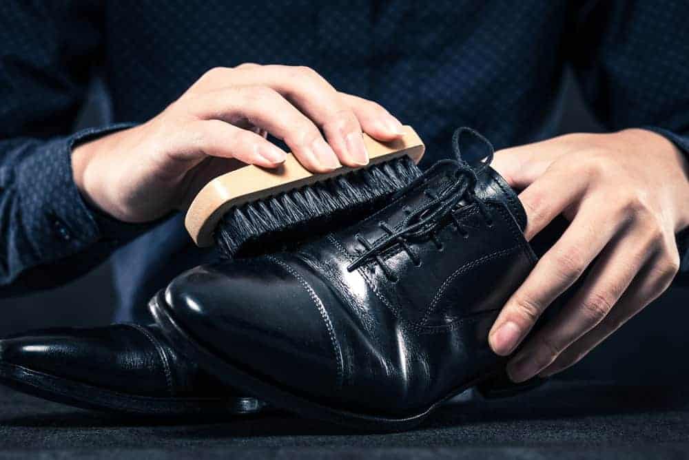 A close look at a man polishing his black leather shoes.