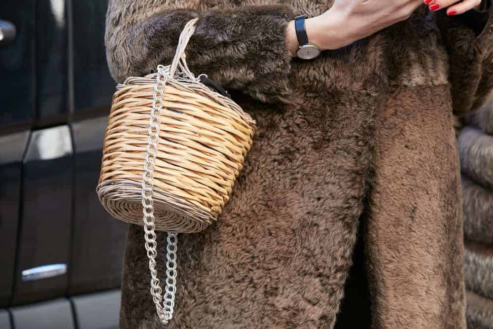 Woman in a brown fur coat with wicker basket bag.