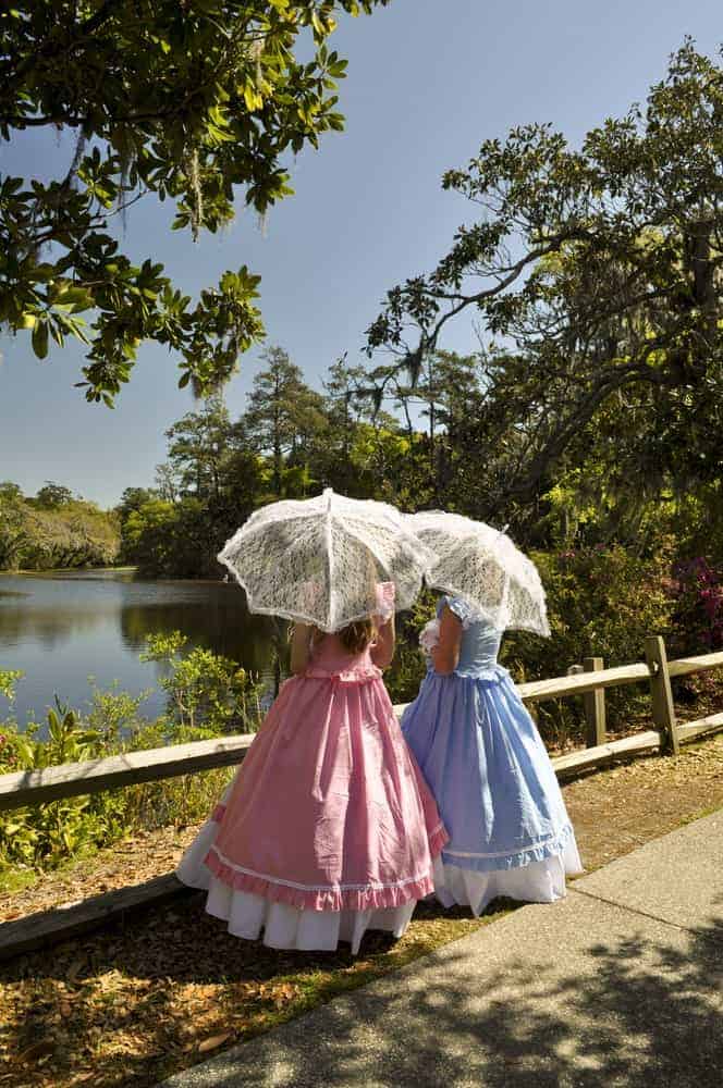 Two Southern belles with umbrellas enjoying the lake view.