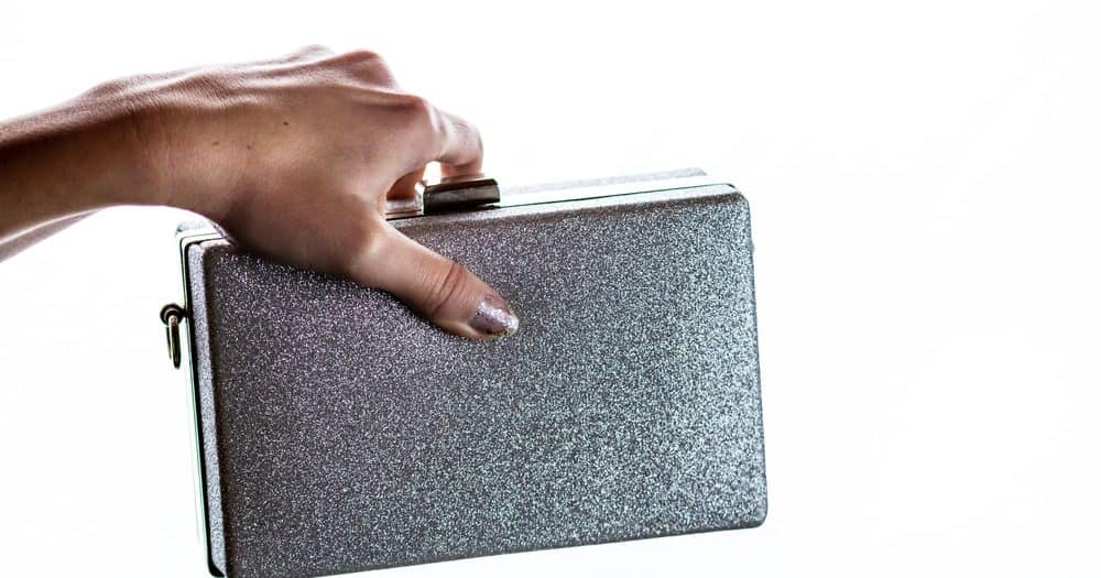 Woman hand holding a glittery silver clutch bag.