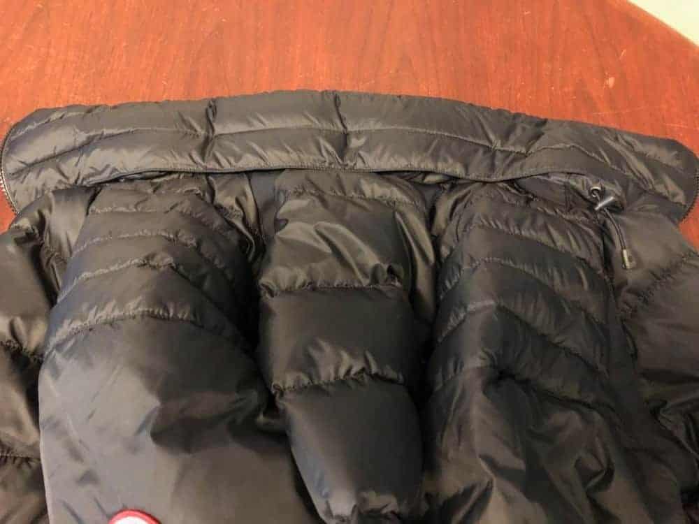 Rear collar of Canada Goose jacket with hood tucked into pocket.