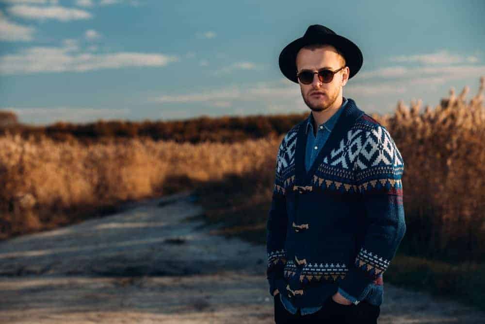 Man wearing a hat and cardigan sweater during autumn.