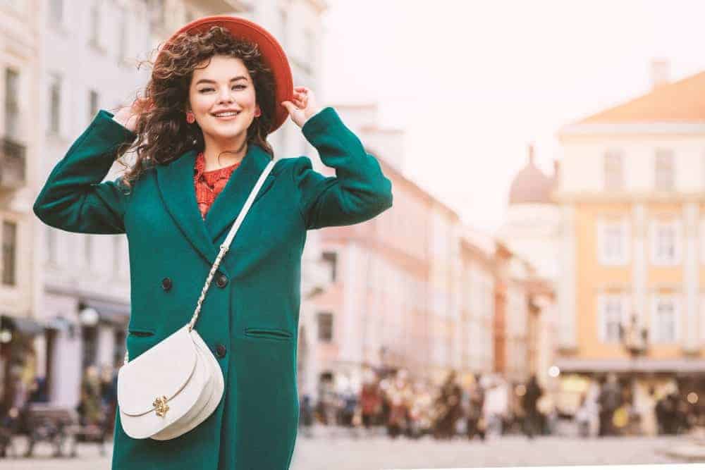 Lady in green coat with white crossbody bag.