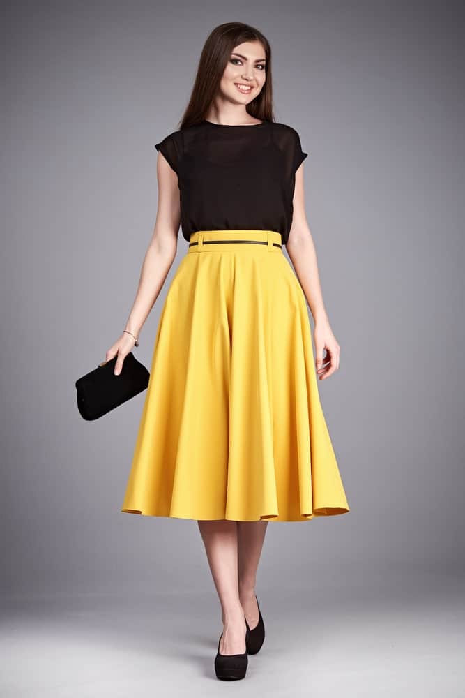 Woman in black blouse and yellow flared skirt.