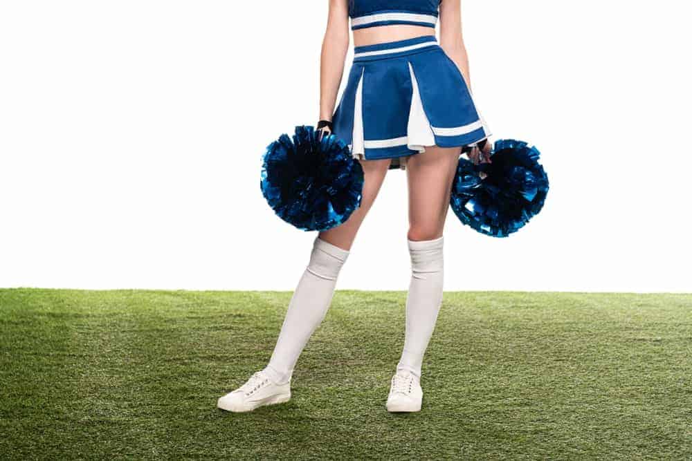 Cheerleader in a blue godet skirt holding pom poms.