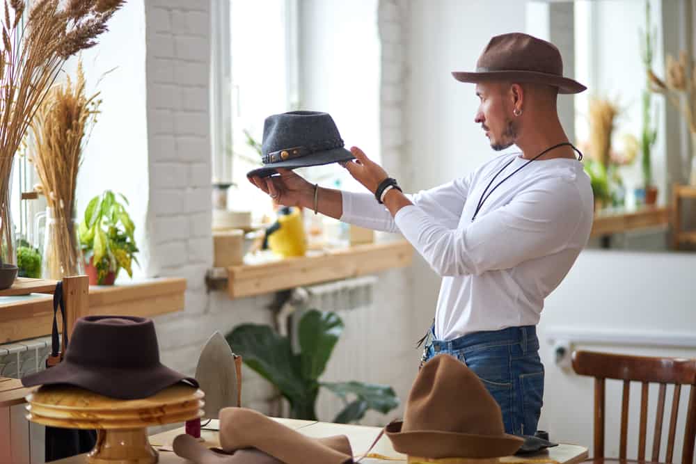 Man holding a hat in his workshop.
