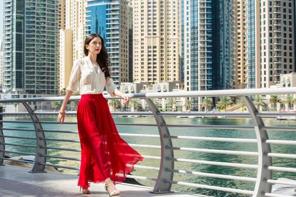 Woman in red maxi skirt walking alongside Dubai Marina Middle East.
