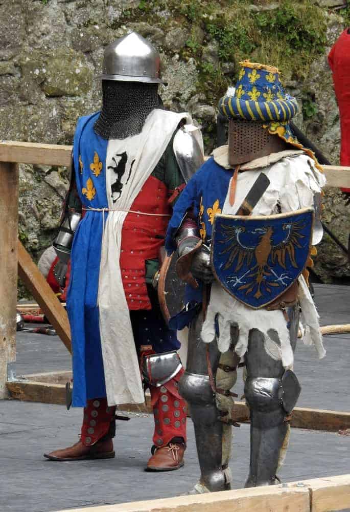 Two knights in full plate armor and decorative medieval surcoats.