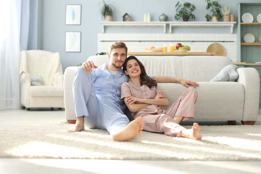 Couple in their pajamas sitting on the floor.