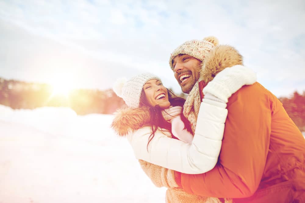 A couple hugging and laughing outdoors during winter.