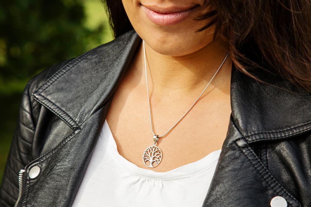 Woman wearing a silver chain with a mandala tree pendant.