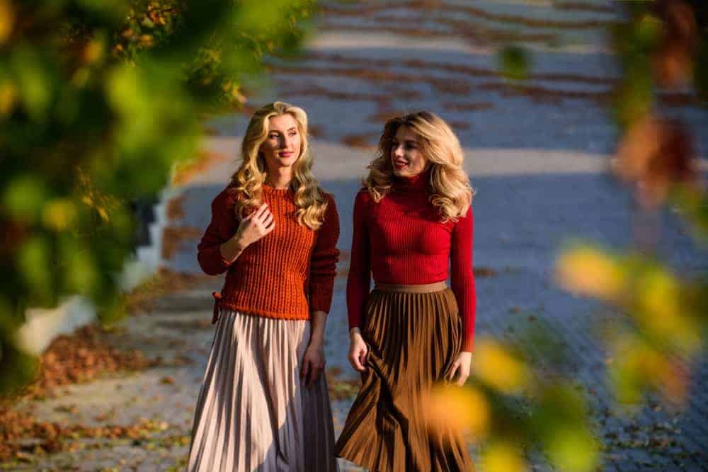 Women wearing sweaters and pleated skirts during autumn.