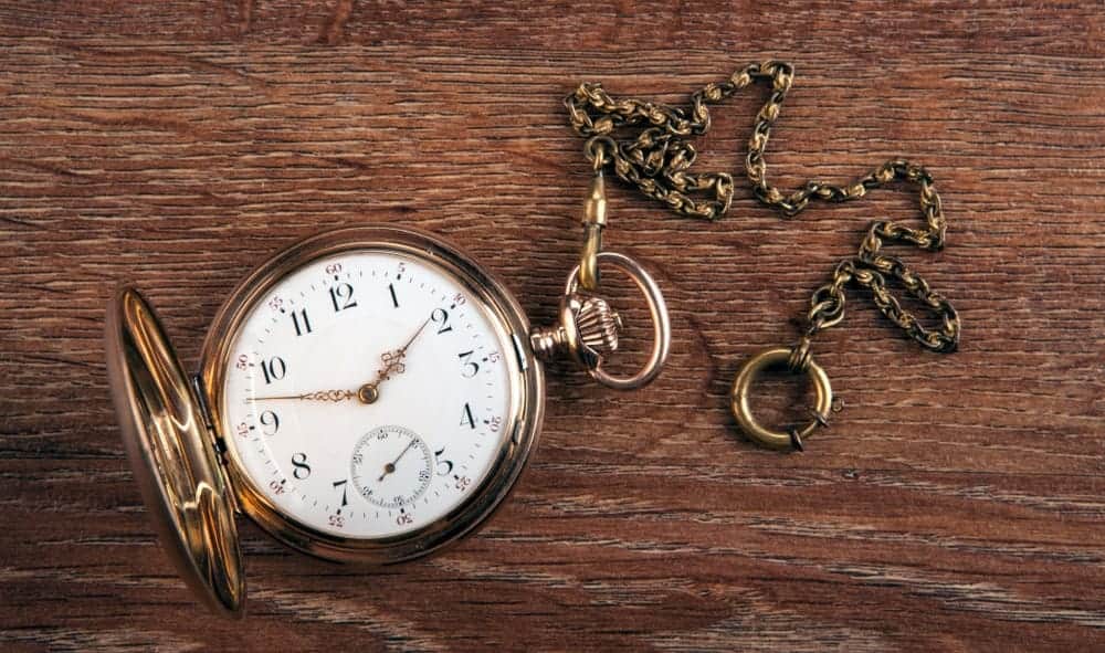 Antique gold pocket watch on a wooden table.
