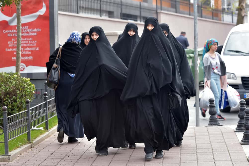 Turkish women in traditional Islamic clothing walking along the city street.