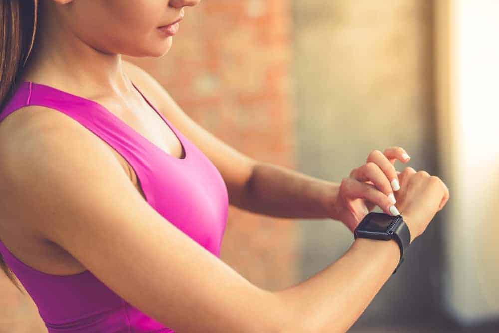 A woman setting her smartwatch before her exercise.
