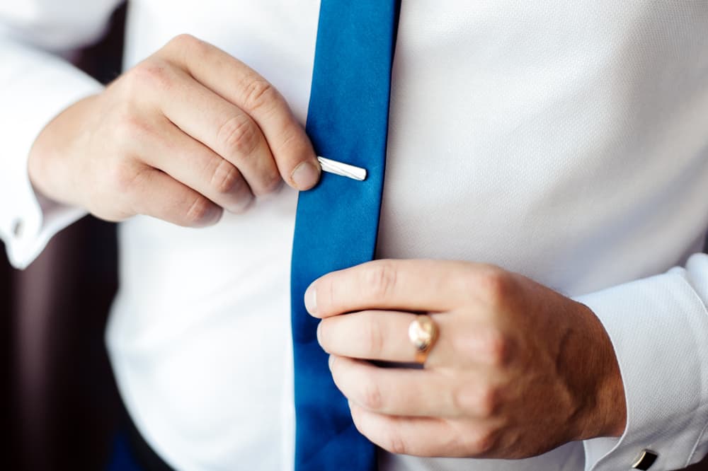 Close-up of a man fastening a tie clip.