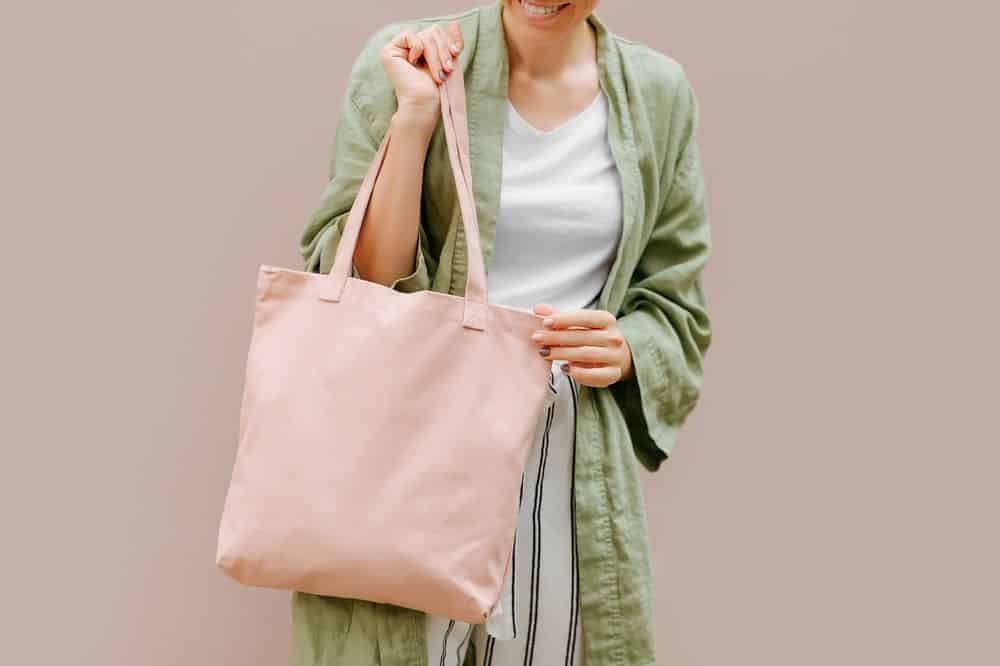 Woman holding canvas tote bag.