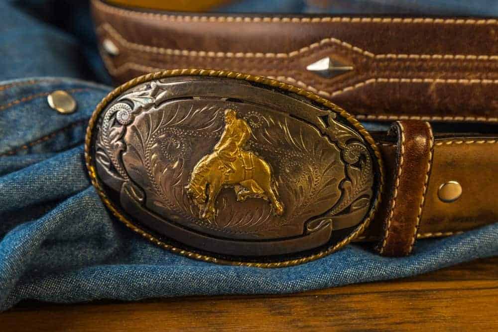A belt with Vintage gold cowboy buckle on it.
