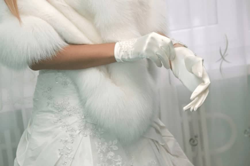 A woman putting on her white silk gloves.