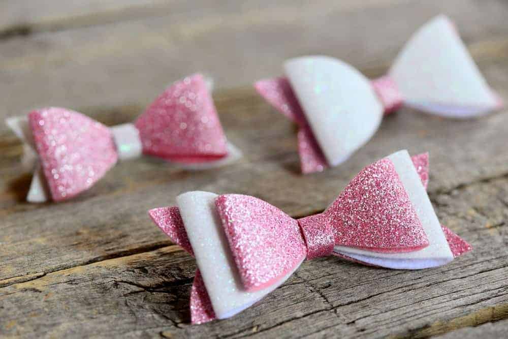 Three pink and white hair bows on a wooden surface.
