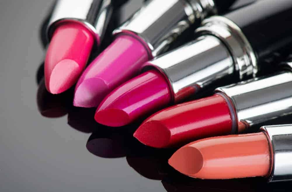 Different colorful lipsticks on display on a black surface.