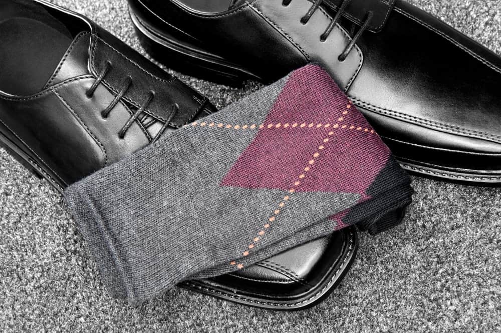 A nice pair of gray socks with formal black leather shoes.