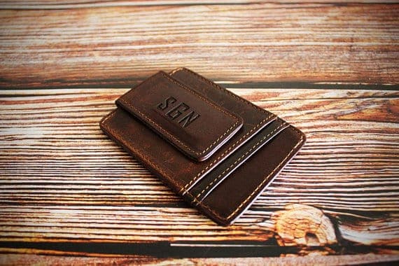 A money clip wallet made of brown leather.