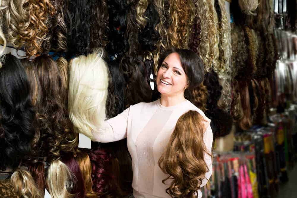 A woman browsing through the wigs on display at a store.
