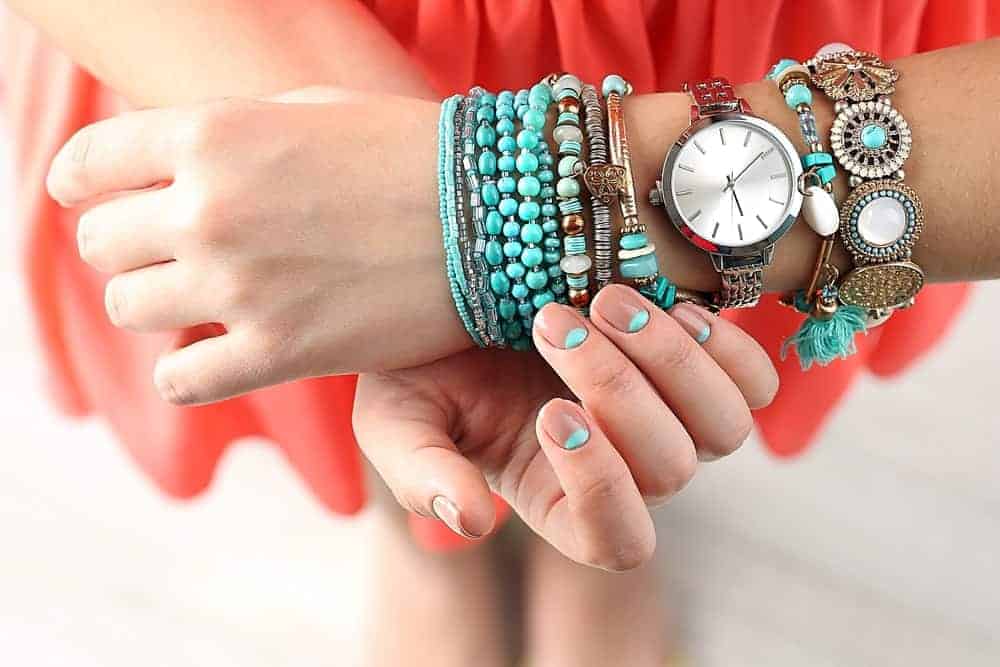 A look at a woman's wrist wearing different types of bracelets.