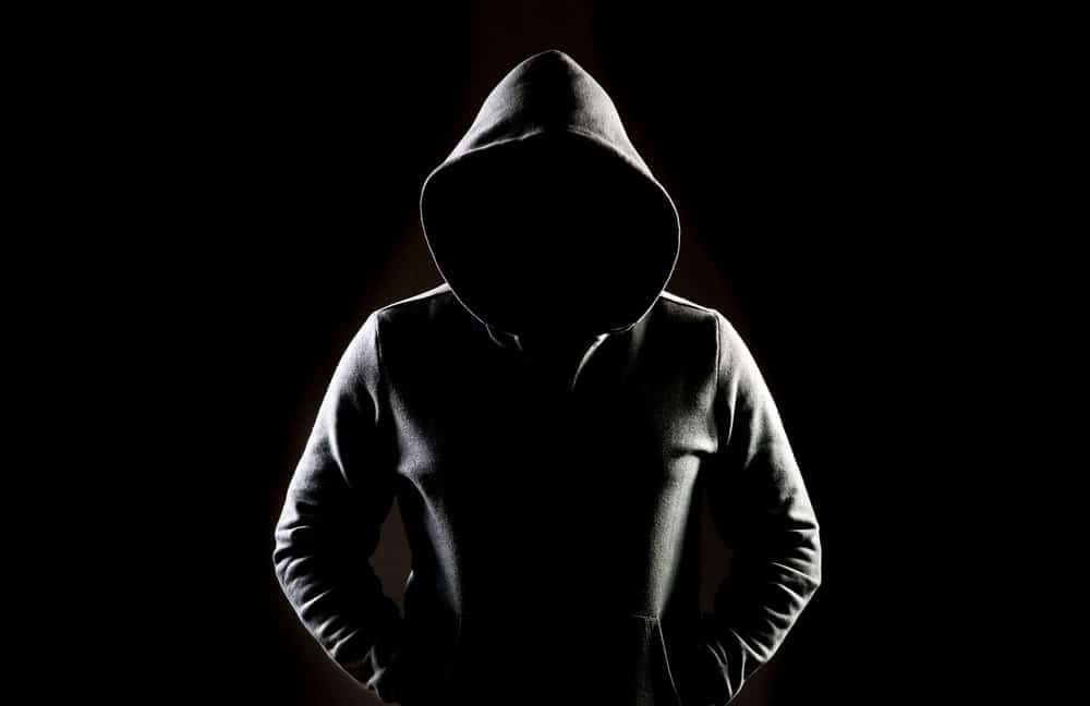The dark outline of a man wearing a hoodie in the shadows.