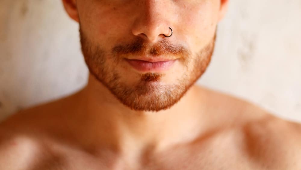 A close look at a man with a nose piercing.