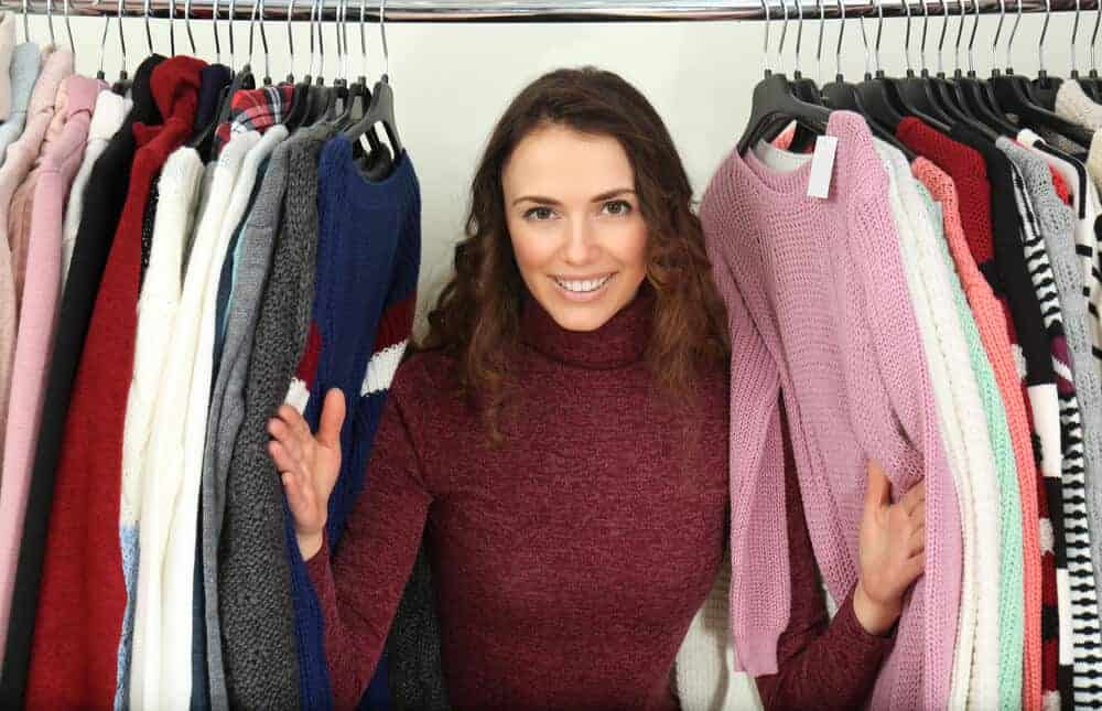 Woman peeking from a rack of different tops.