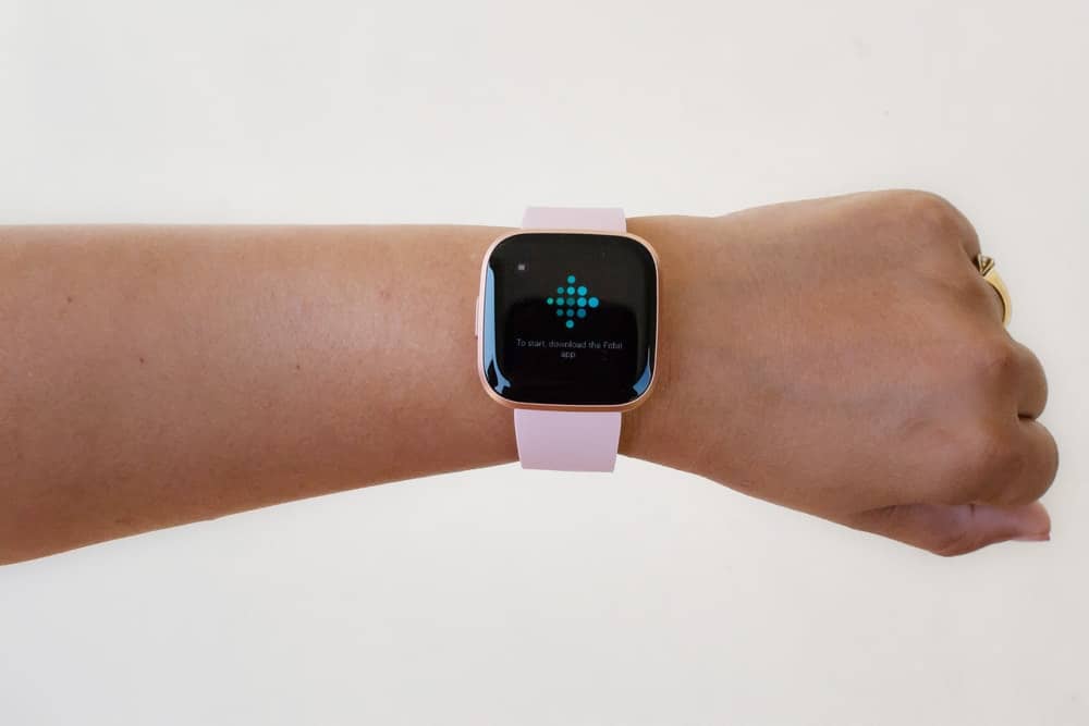 A woman wearing a Fitbit with pink straps.