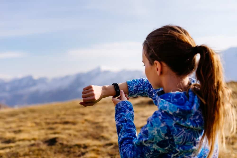 A woman on a jog checking her health tracker.