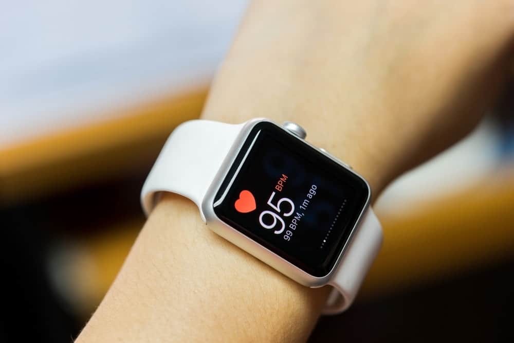 A woman wearing a smartwatch with white straps.
