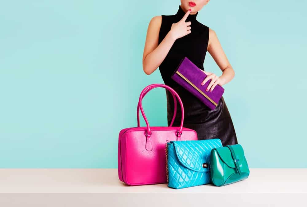 A woman deciding which purse or handbag to use.