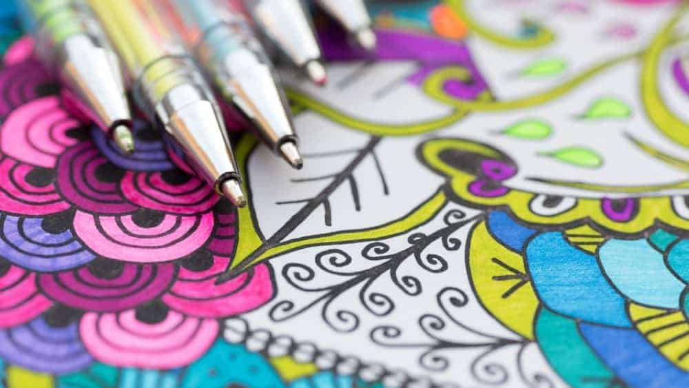 A close look at gel pens on a background of colorful illustrations.