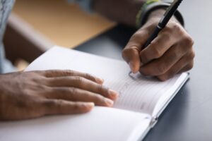 Person writing with a pen in a blank book