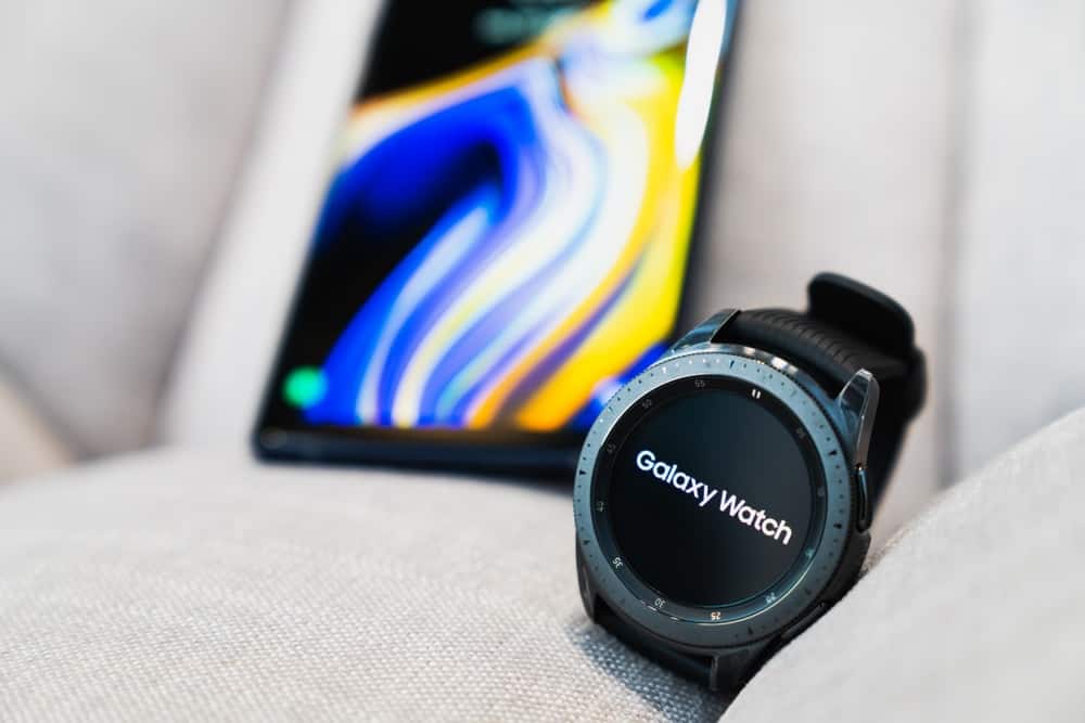 A close look at a Samsung Galaxy Watch and a mobile phone in the background.