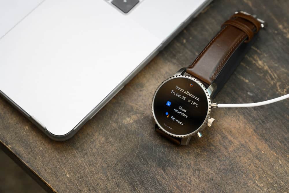 A close look at a smartwatch connected to the computer with a wire.