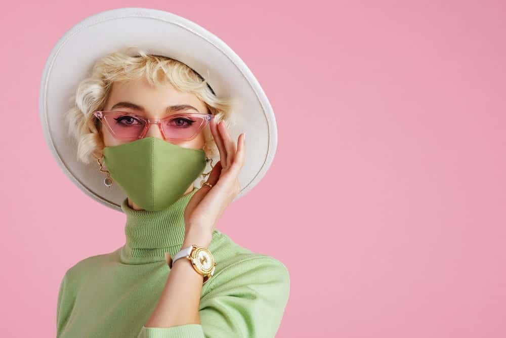 A stylish woman wearing a green turtleneck with her green mask.