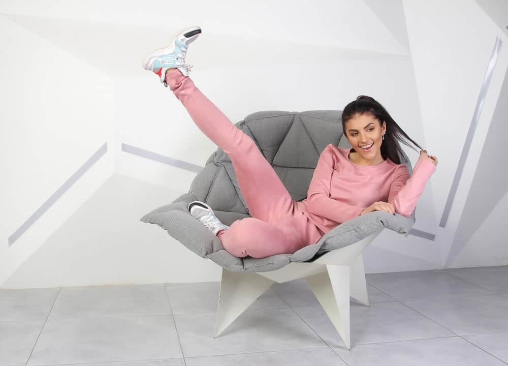A woman lounging at home wearing a pair of pink tracksuit.