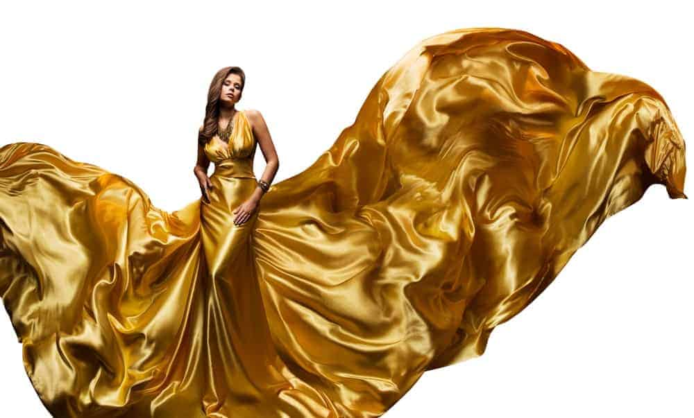 A woman wearing a large golden dress that billows with the wind.