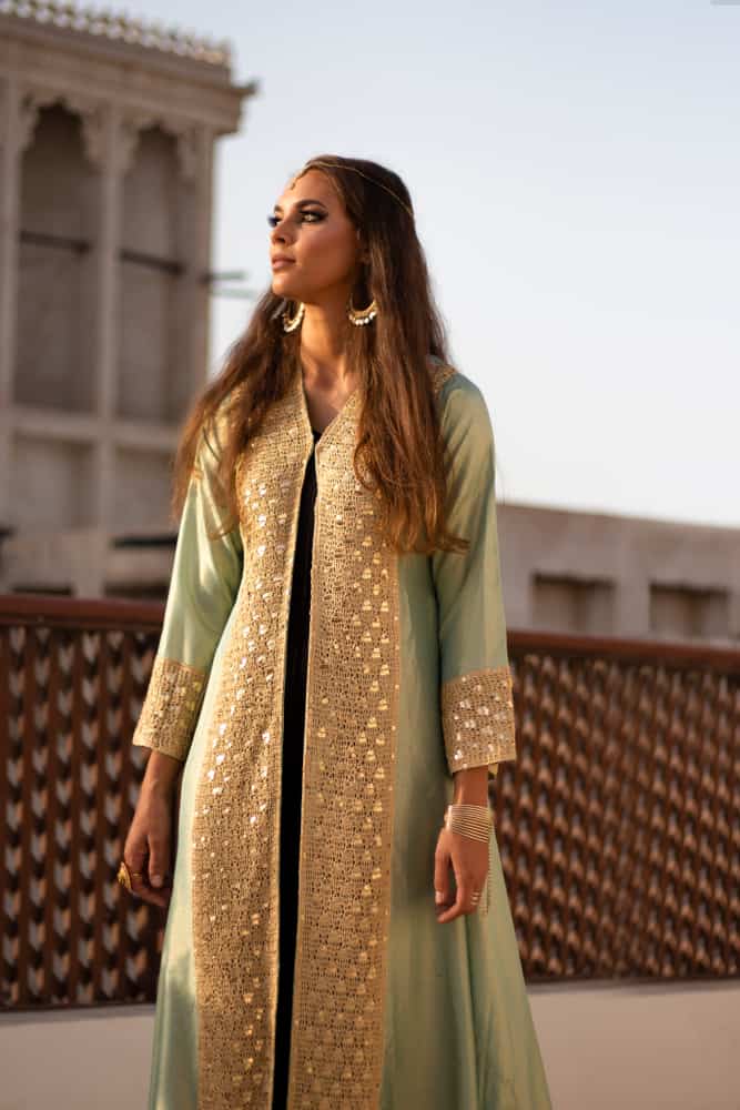 Woman in a balcony wearing a torquoise and golden Arabic kaftan dress.
