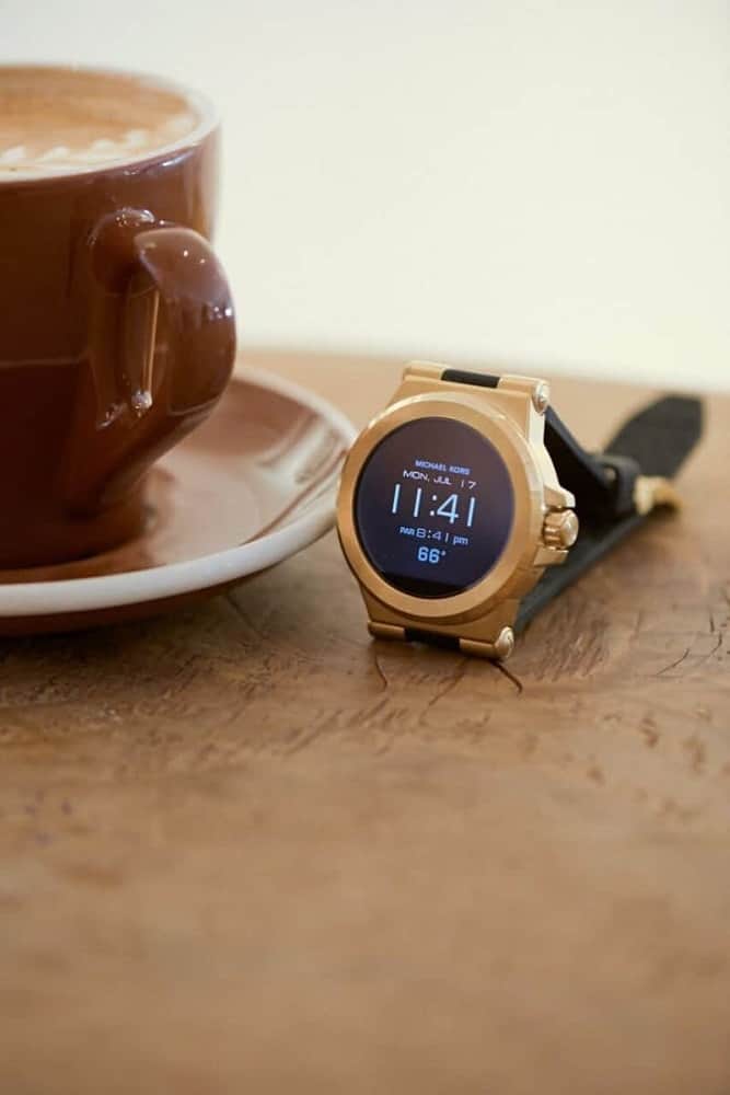 Michael Kors gold smartwatch on a wooden table.
