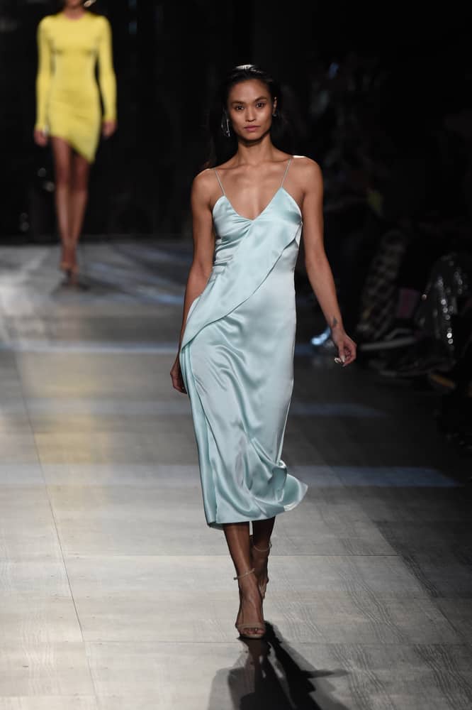 A model in a silk slip dress walks the runway.