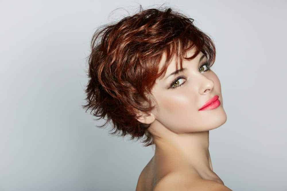 A woman wearing wearing short pixie crop wig in red shade.