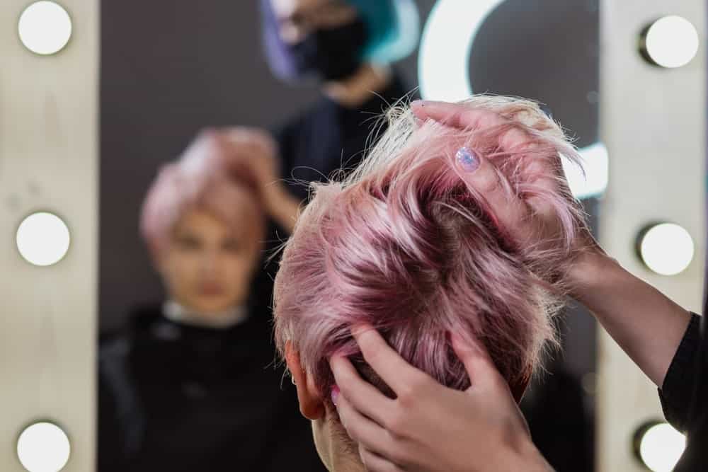 Hairdresser applying a pixie cut wig to a woman client.