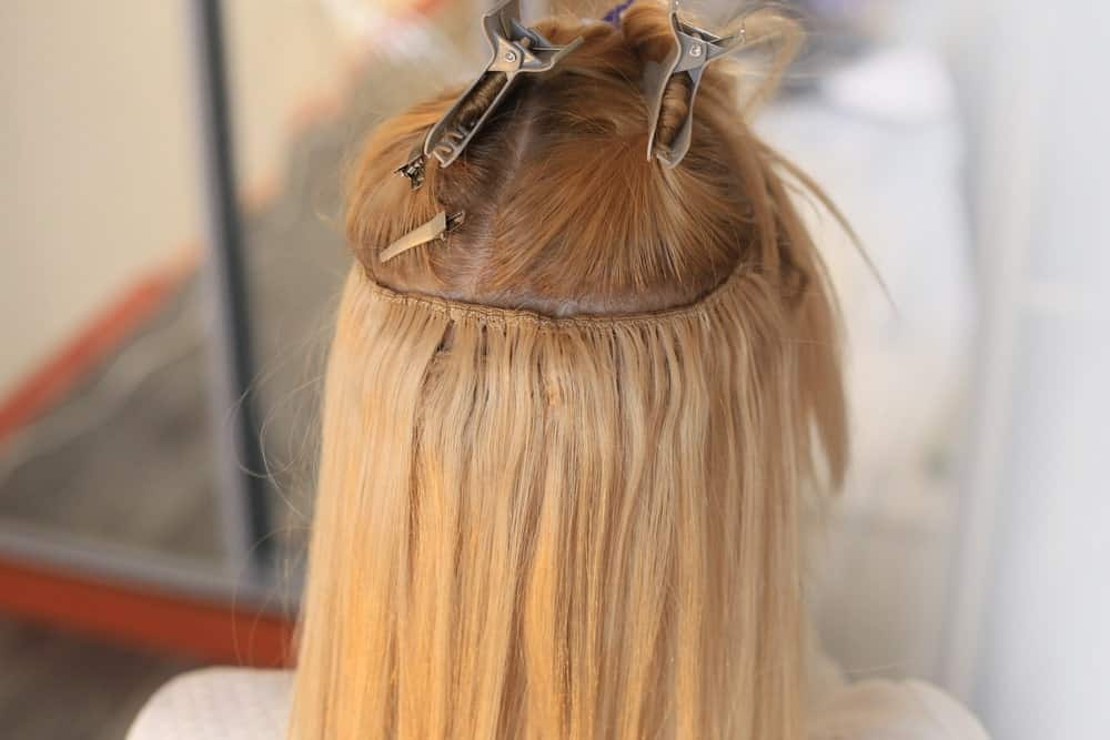 Woman's blonde hair sewn on a pigtail with hair extensions.